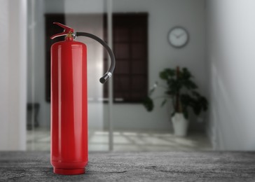 Fire extinguisher on black slate table indoors. Space for text