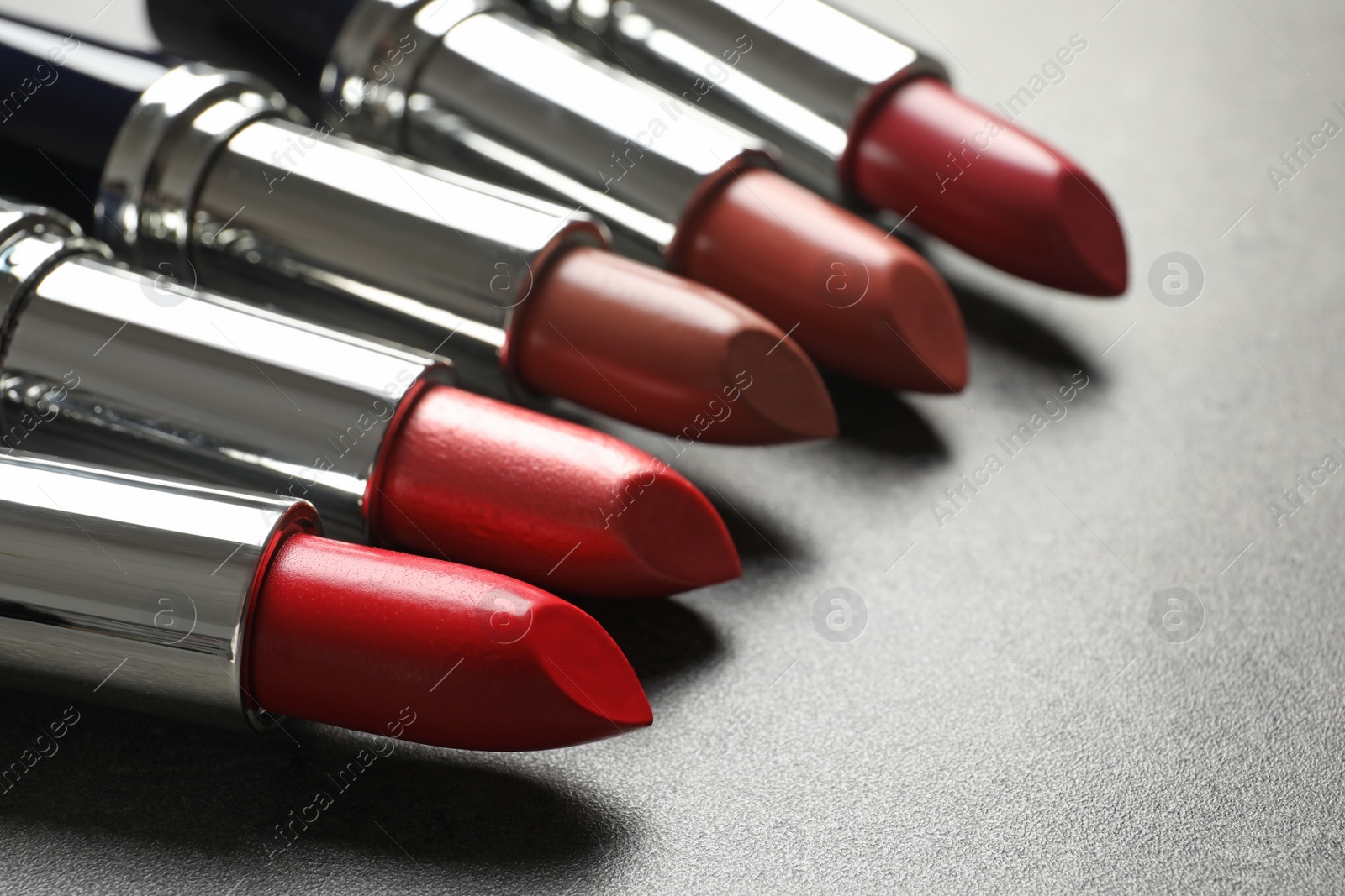 Photo of Set of different lipsticks on grey background, closeup