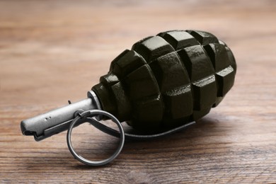 Photo of Hand grenade on wooden table, closeup. Explosive weapon