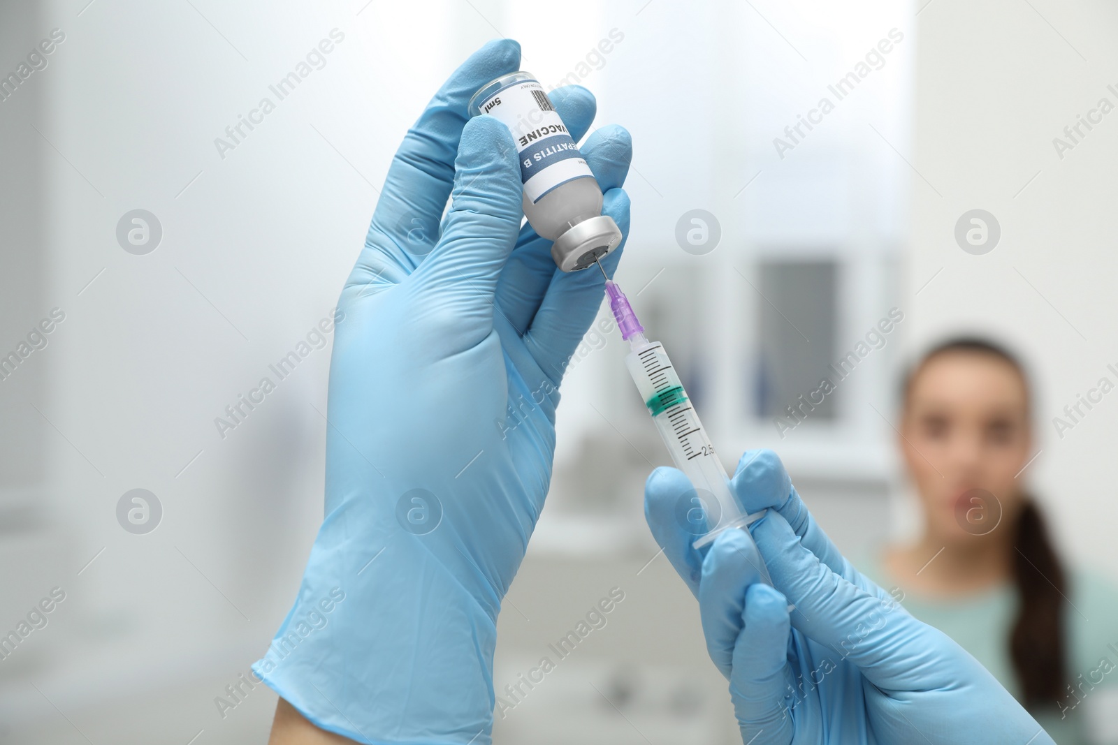 Photo of Woman waiting to get hepatitis vaccine at clinic. Doctor filling syringe from glass vial, closeup