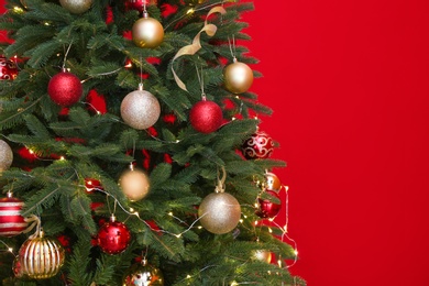 Beautiful Christmas tree with fairy lights and festive decor on red background