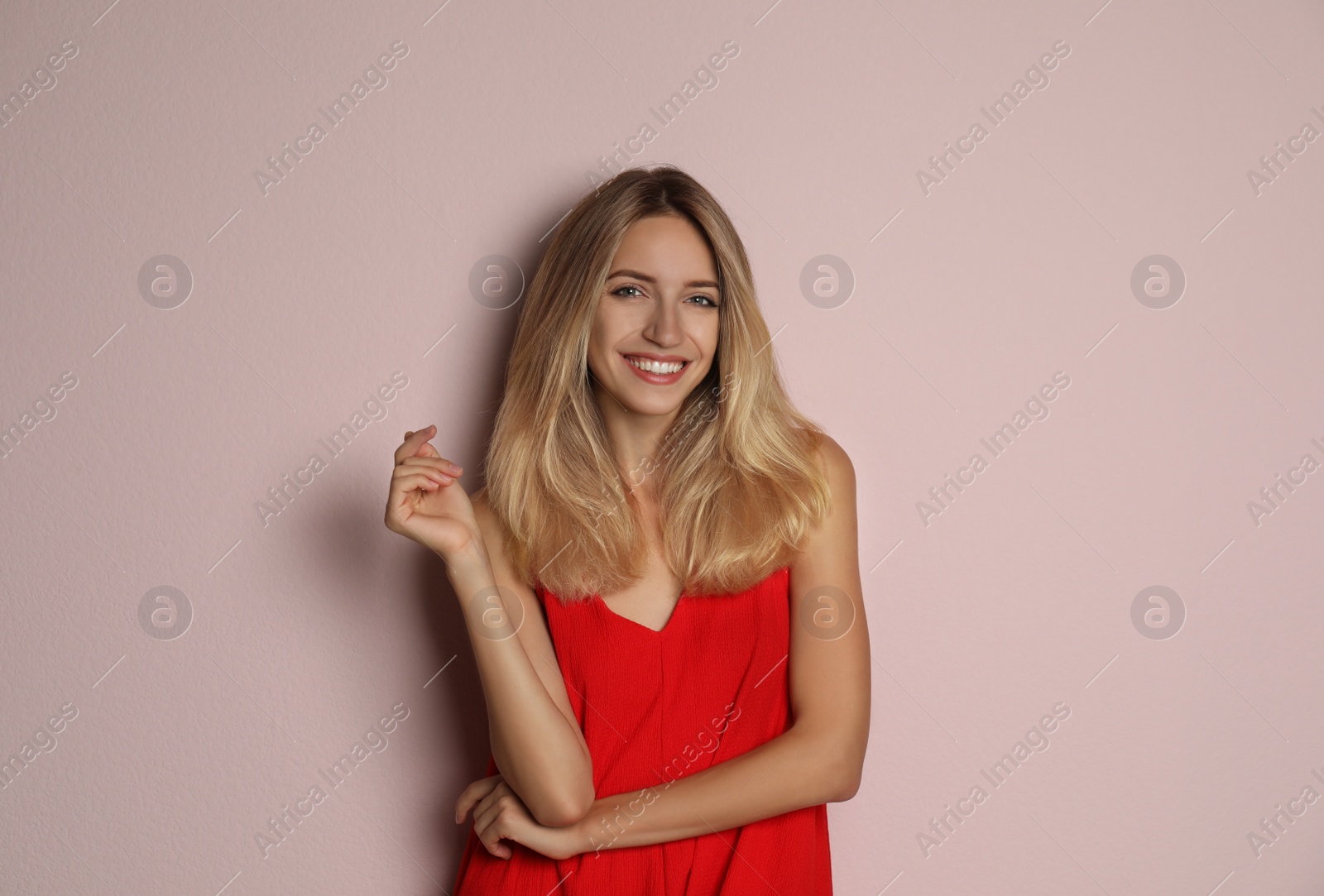 Photo of Young woman wearing stylish red dress on pale pink background