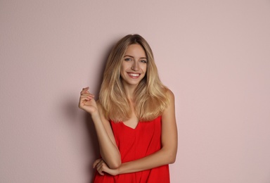 Young woman wearing stylish red dress on pale pink background