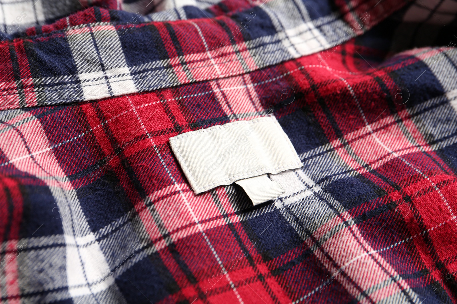 Photo of Blank clothing label on checkered shirt, closeup