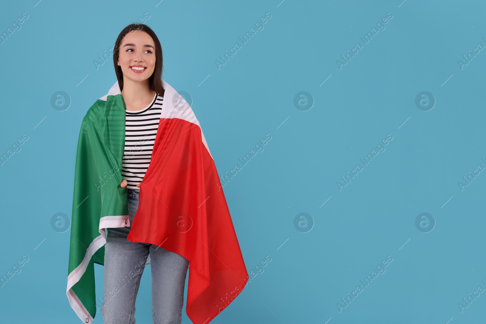 Photo of Young woman with flag of Italy on light blue background, space for text