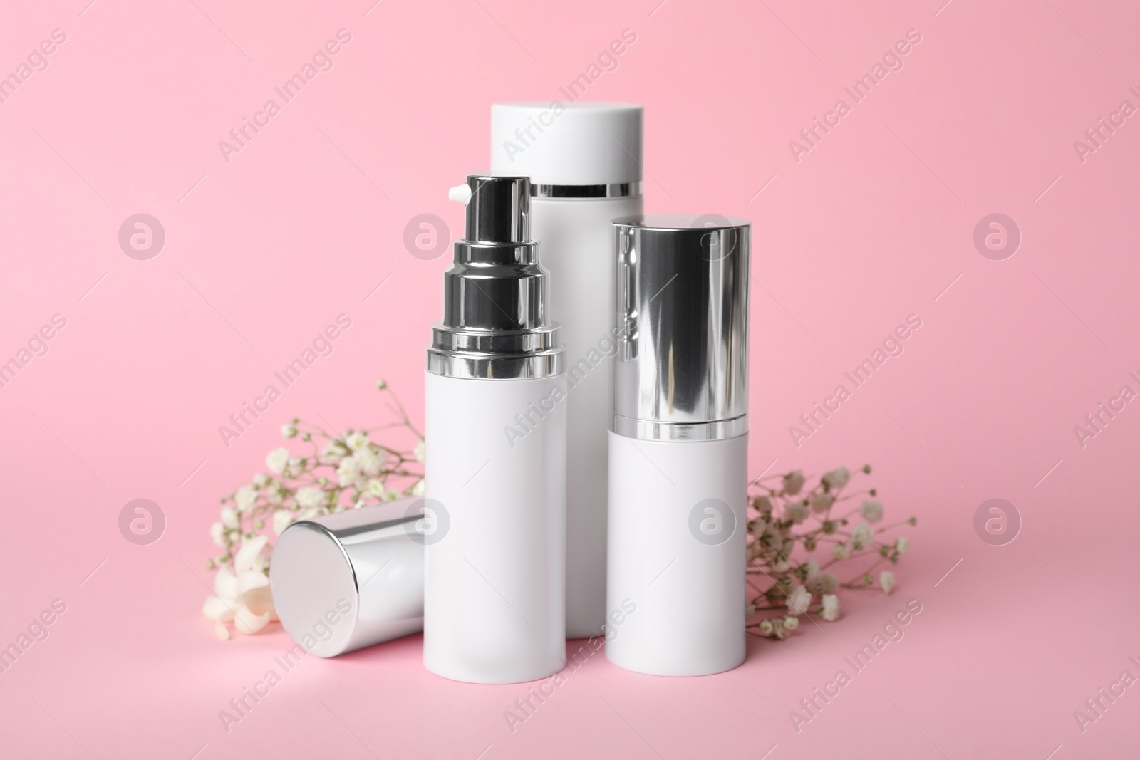 Photo of Set of luxury cosmetic products and flowers on pink background