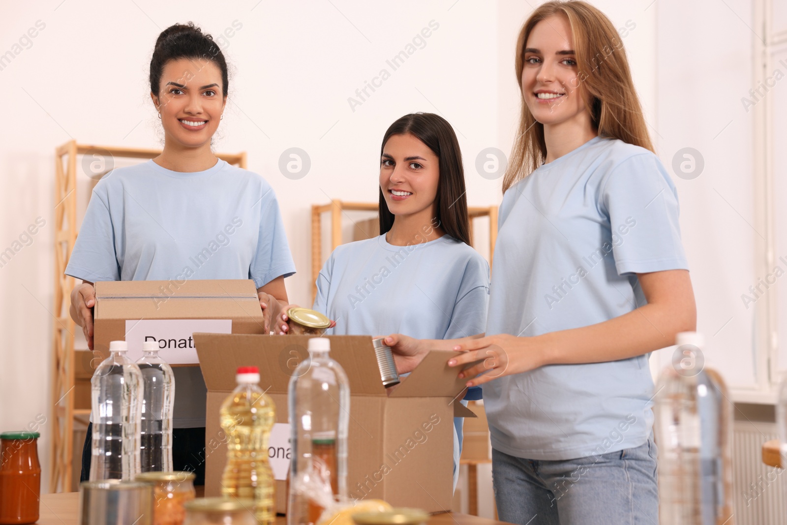 Photo of Portrait of volunteers packing food products at table in warehouse