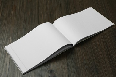 Open blank paper brochure on wooden table. Mockup for design