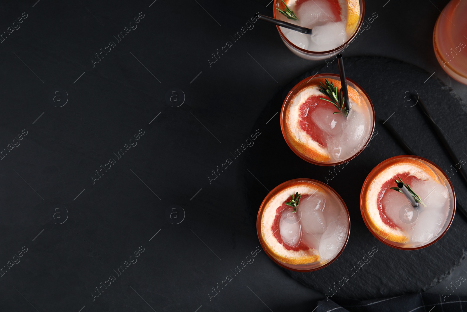 Photo of Flat lay composition with glasses of grapefruit cocktails on dark background. Space for text