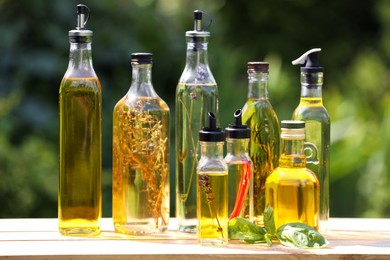 Many different cooking oils on wooden table against blurred green background