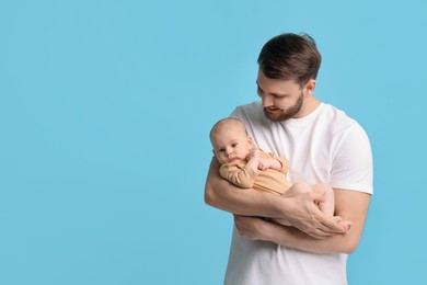 Father with his cute baby on light blue background, space for text