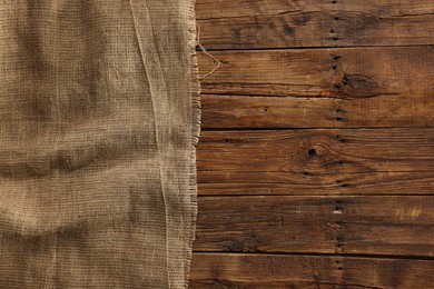 Burlap fabric on wooden table, top view. Space for text