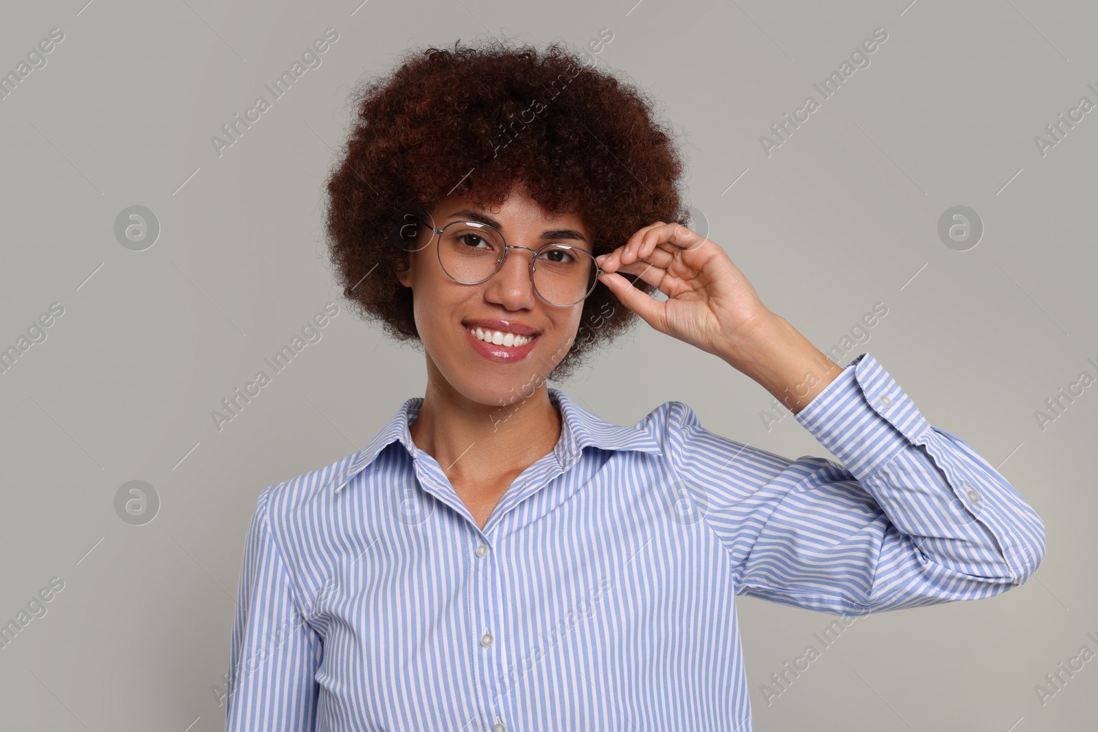 Photo of Portrait of happy young woman in eyeglasses on grey background