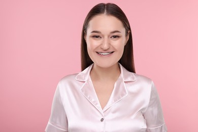Photo of Smiling woman with dental braces on pink background