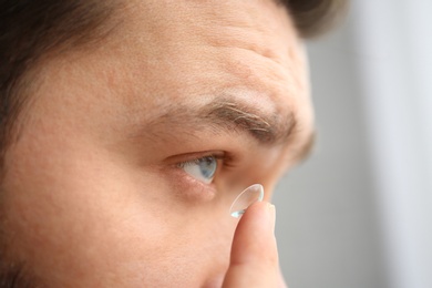 Photo of Man putting contact lens in his eye, closeup