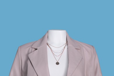 Photo of Female mannequin dressed in white t-shirt with necklace and stylish leather jacket on light blue background
