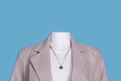 Female mannequin dressed in white t-shirt with necklace and stylish leather jacket on light blue background