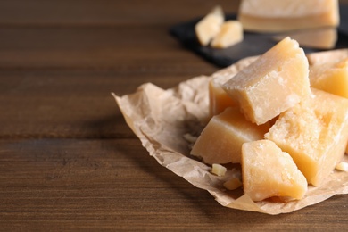 Pieces of delicious parmesan cheese on wooden table, closeup. Space for text