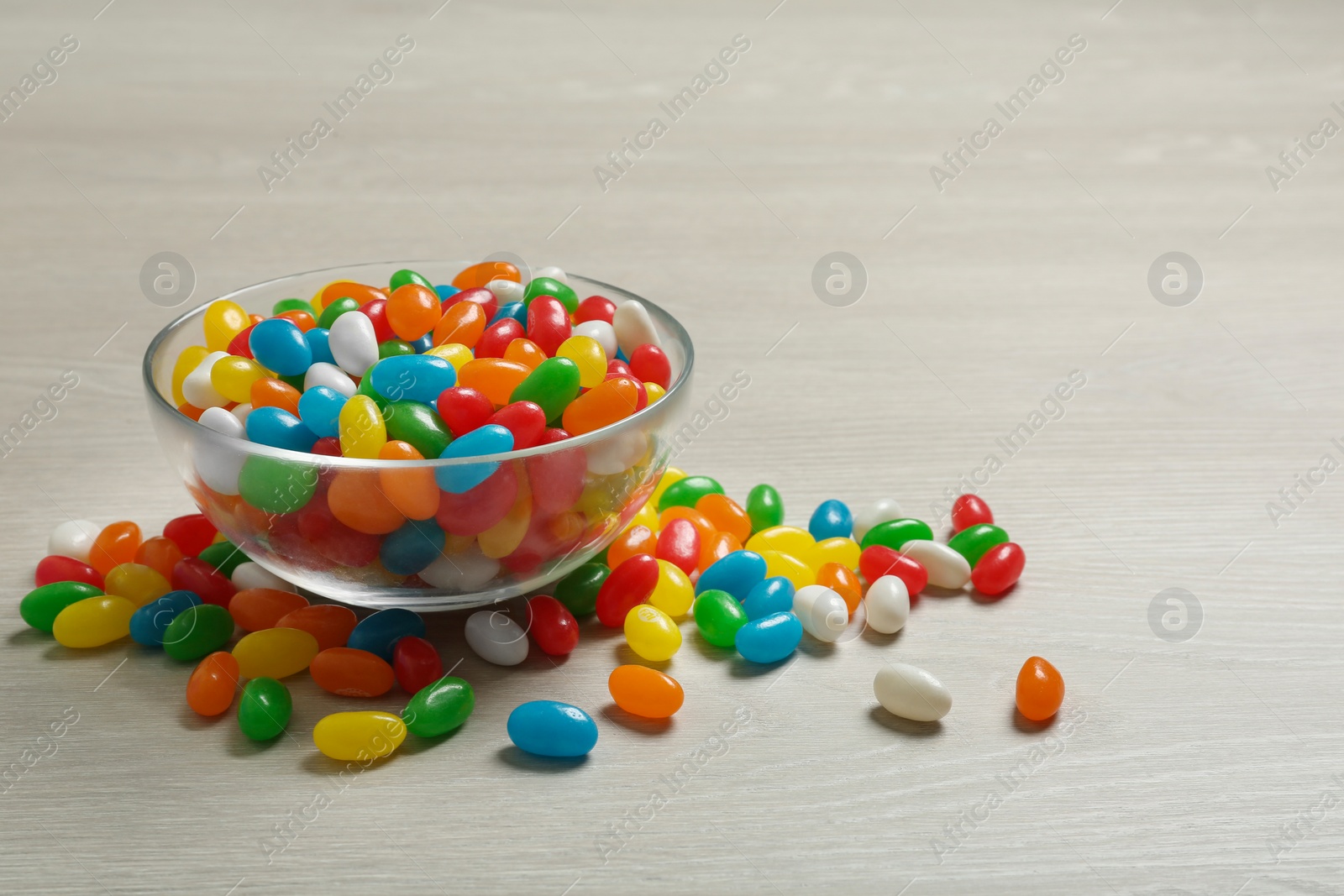 Photo of Bowl of delicious jelly beans on table. Space for text