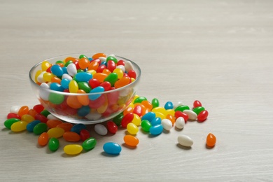 Bowl of delicious jelly beans on table. Space for text