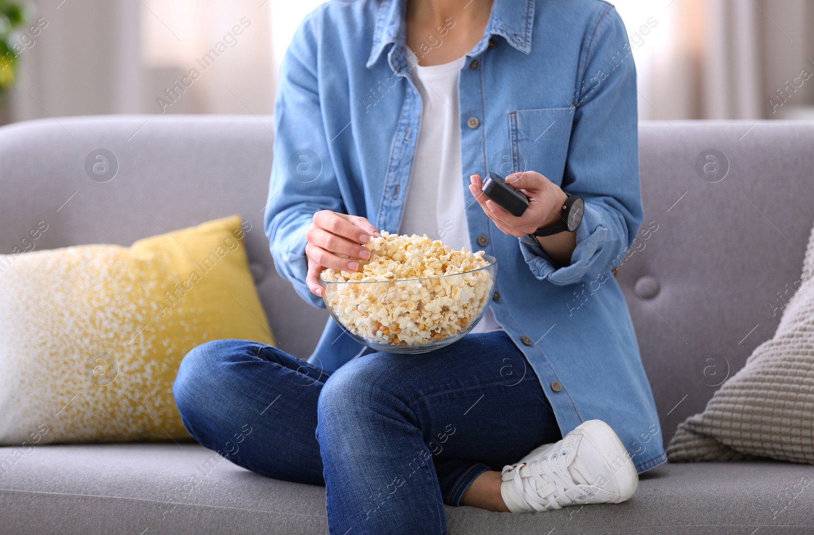 Photo of Young woman watching movie with popcorn in living room, closeup