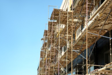 View of unfinished building with scaffolding against blue sky, space for text