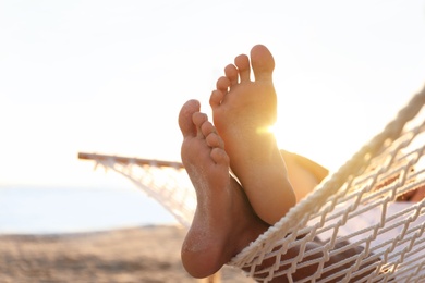 Photo of Man relaxing in hammock on beach at sunset, closeup