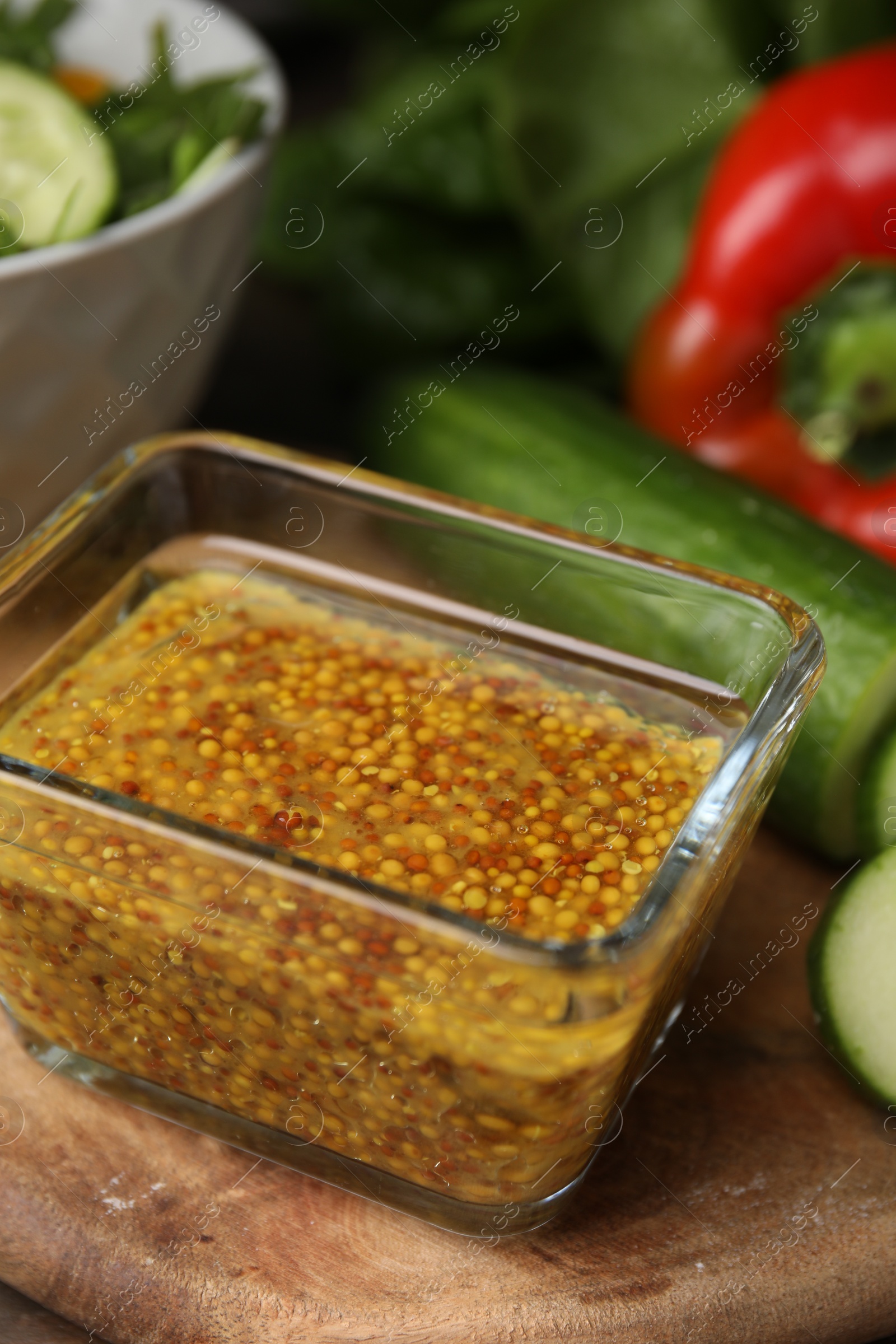 Photo of Tasty vinegar based sauce (Vinaigrette) in bowl and products on wooden table, closeup