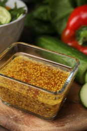 Tasty vinegar based sauce (Vinaigrette) in bowl and products on wooden table, closeup