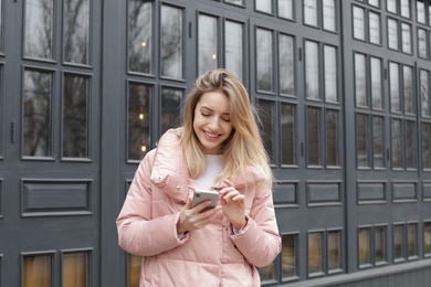 Photo of Beautiful young woman using mobile phone outdoors