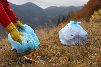 Woman with trash bag collecting garbage in nature, closeup