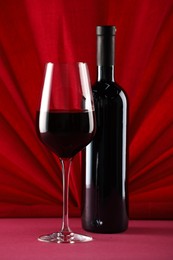 Stylish presentation of delicious red wine in bottle and glass on color background