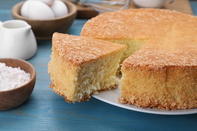 Photo of Tasty sponge cake and ingredients on light blue wooden table, closeup