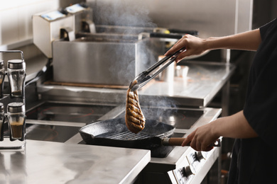 Photo of Female chef cooking chicken fillet on stove in restaurant  kitchen, closeup