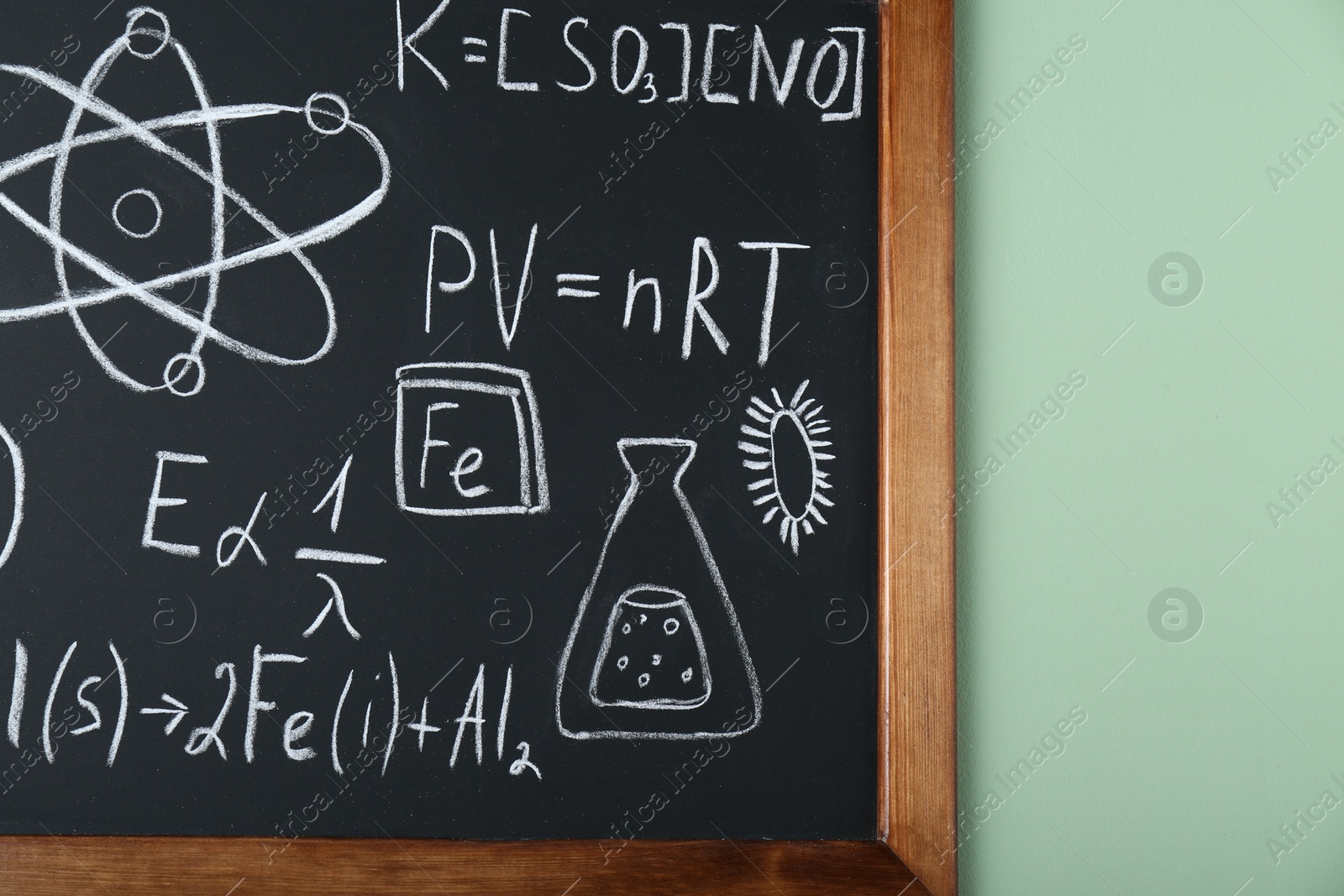 Photo of Blackboard with different chemical formulas written with chalk on light green wall