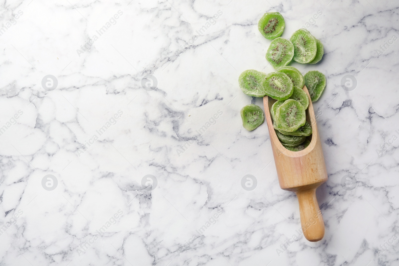 Photo of Scoop of dried kiwi on marble background, top view with space for text. Tasty and healthy fruit