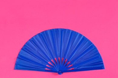 Photo of Blue hand fan on pink background, top view