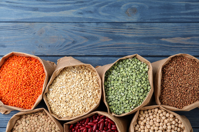 Photo of Flat lay composition with different types of legumes and cereals on blue wooden table, space for text. Organic grains