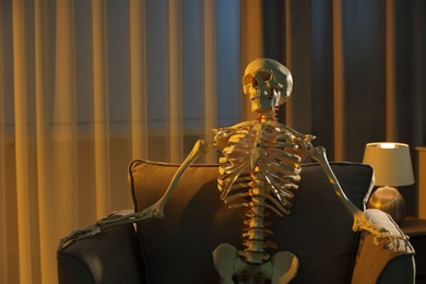 Waiting concept. Human skeleton sitting in armchair indoors