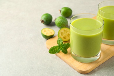 Photo of Fresh feijoa smoothie and fresh mint on grey table, closeup. Space for text