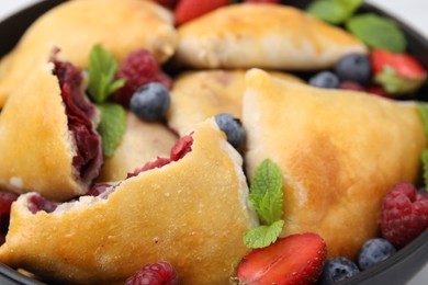 Delicious samosas, berries and mint leaves in bowl, closeup