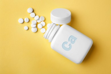 Image of Calcium supplement. Bottles with pills on yellow background, flat lay
