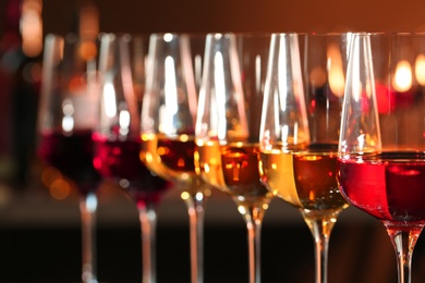 Row of glasses with different wines against blurred background, closeup