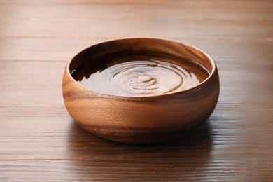 Photo of Bowl with pure water on wooden table