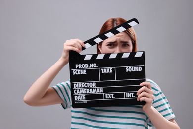Photo of Emotional actress with clapperboard on grey background. Film industry