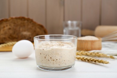 Photo of Glass jar with sourdough on white wooden table