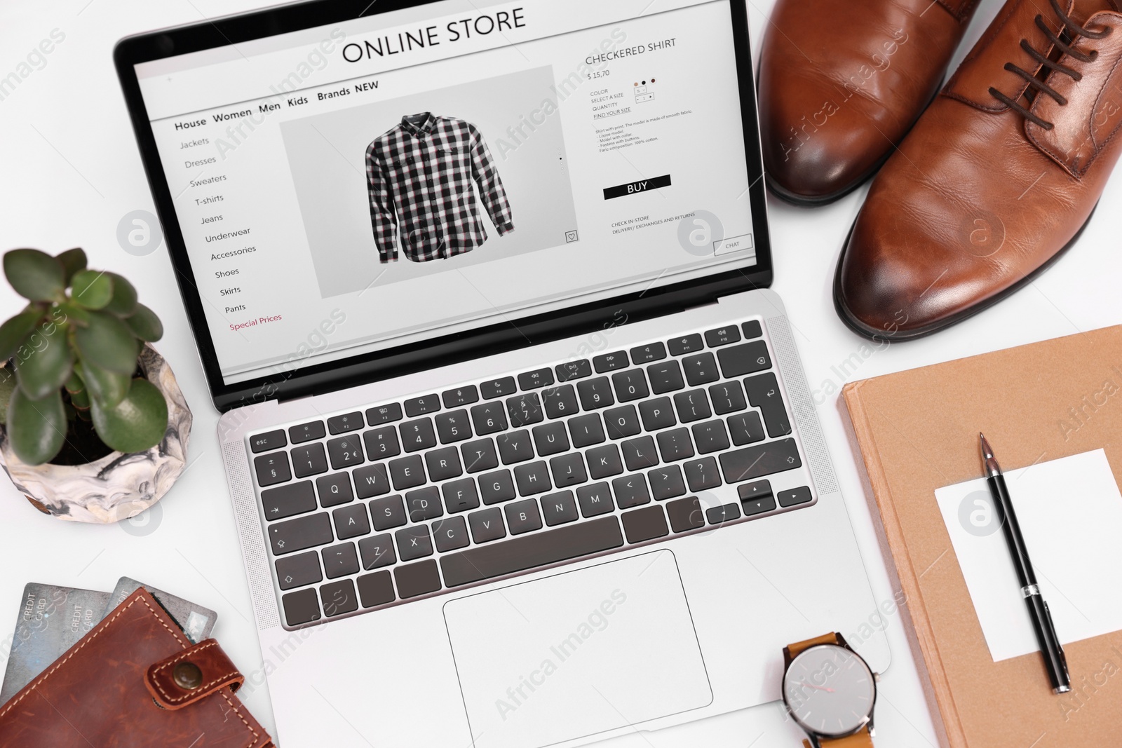 Photo of Online store website on laptop screen. Computer, stationery, credit cards, men's shoes and accessories on white background, above view