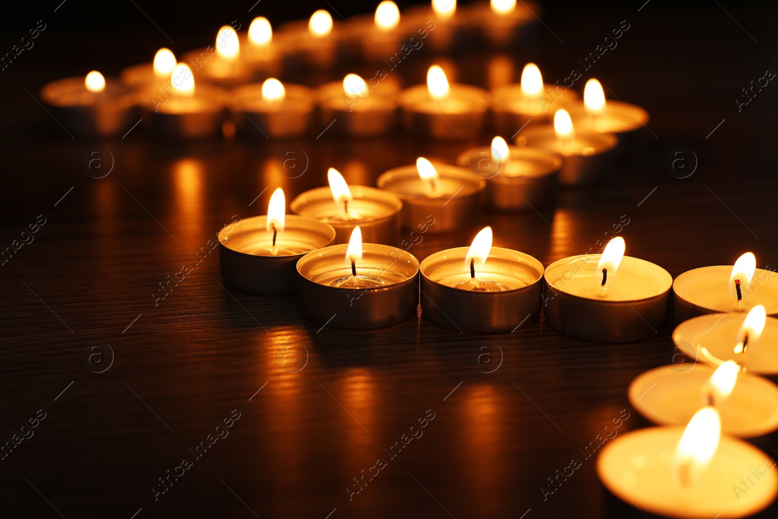 Photo of Burning candles on surface in darkness, closeup