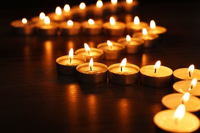 Burning candles on surface in darkness, closeup