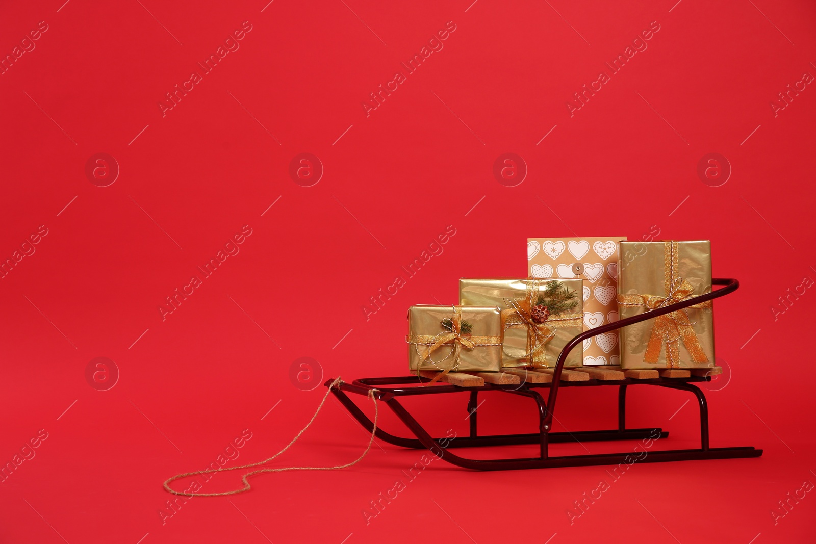 Photo of Sleigh with gift boxes on red background. Space for text